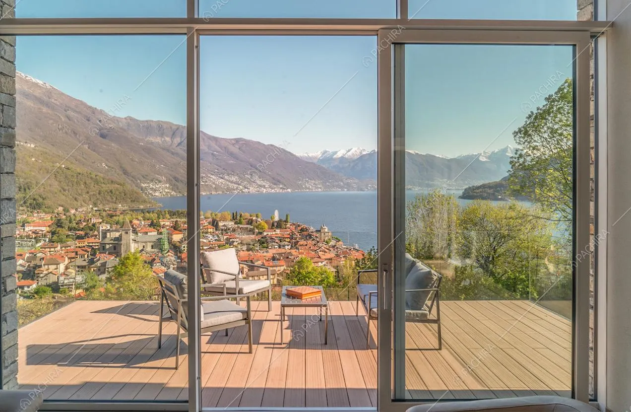Dalla vetrata con porta-finestra del soggiorno vista sulla terrazza con salotto da esterni e pavimento in parquet