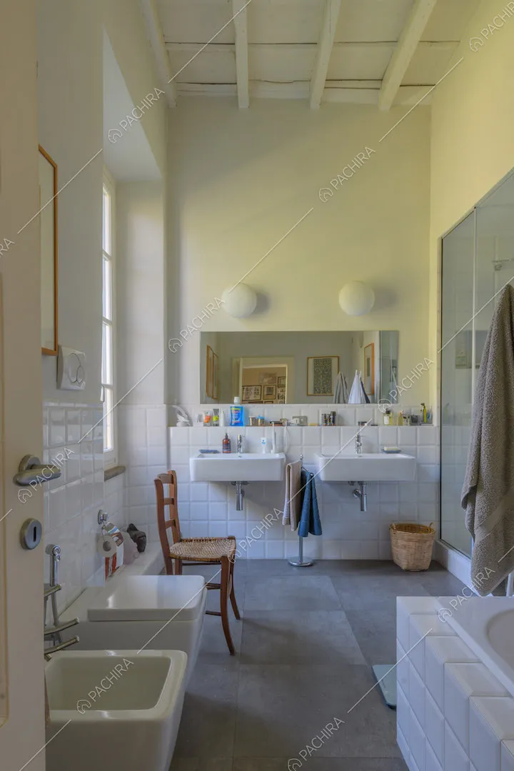 Ampio bagno con piastrelle bianche sulle pareti, vasca e soffitto a cassettoni