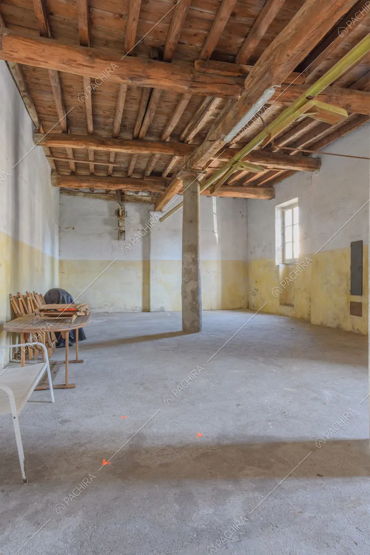 Grande carage con colonne, pareti gialle e bianche e soffitto in travi in legno