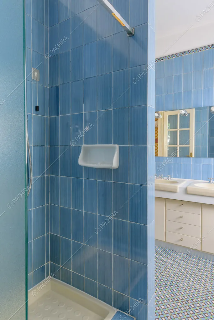 Box doccia nel bagno con pareti in piastrelle azzurre e doppio lavandino