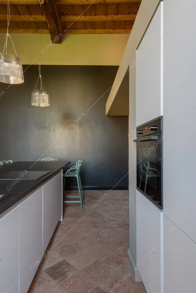 Pavimento in cotto nella luminosa cucina con parete nera e gialla