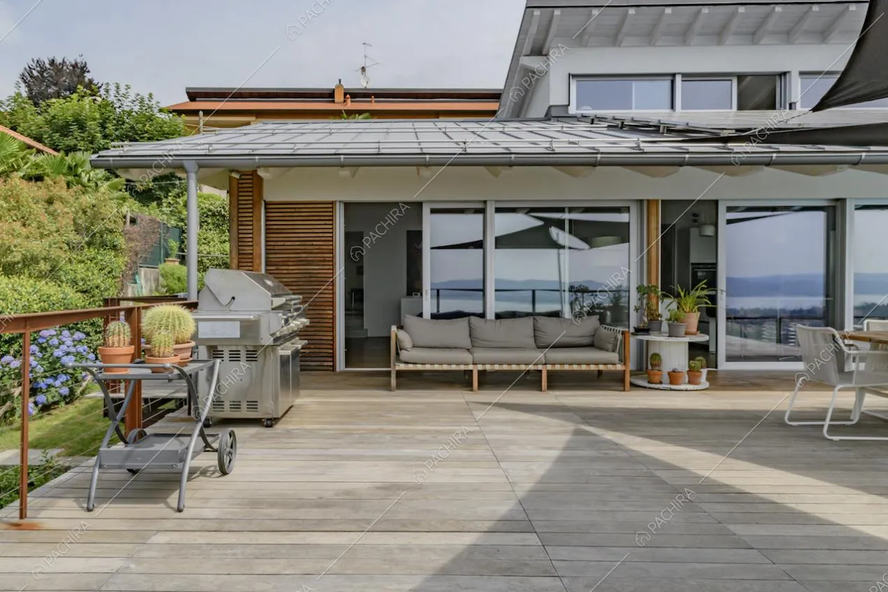 Terrazza con pavimento in parquet da esterni, barbecue, veranda con divano e porte-finestre scorrevoli