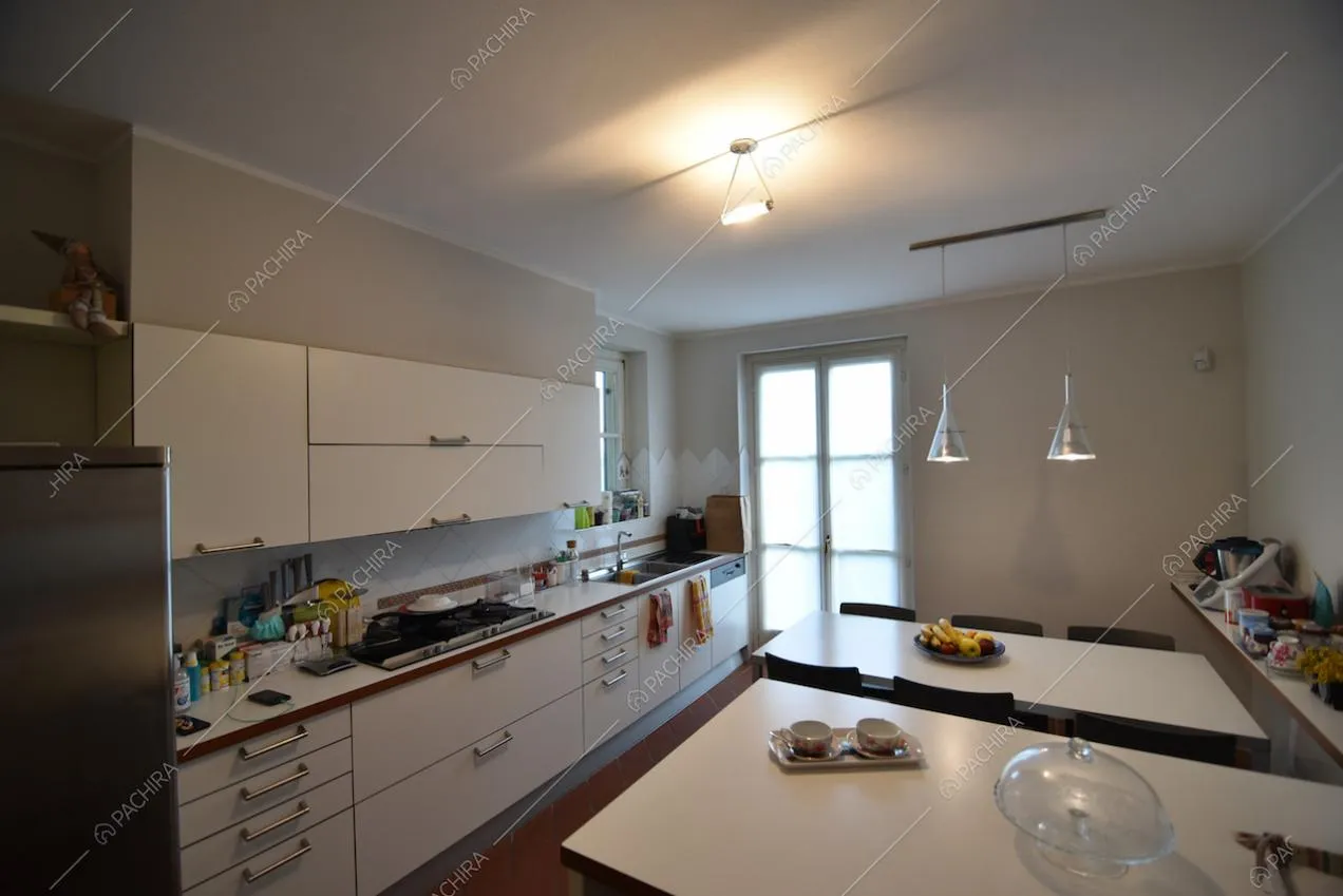 Cucina con mobili bianchi e tavolo da pranzo