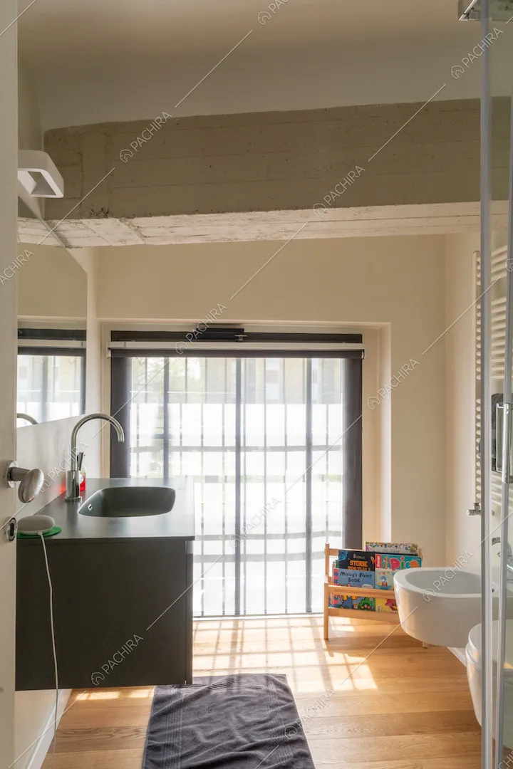 Bagno con mobile sospeso, pavimento in parquet e ampia finestra in stile industriale