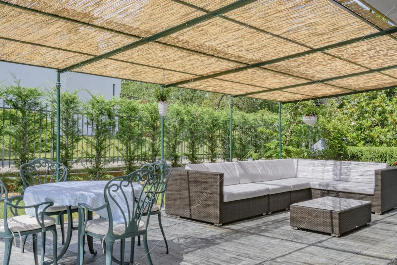 Veranda aperta con divano angolare in vimini e tavolo da esterni