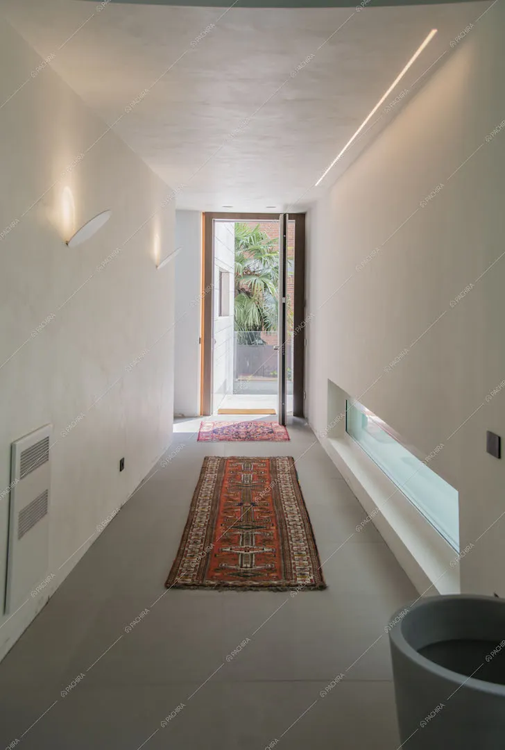 Dal corridoio con pavimento grigio e pareti bianche vista sull'ingresso