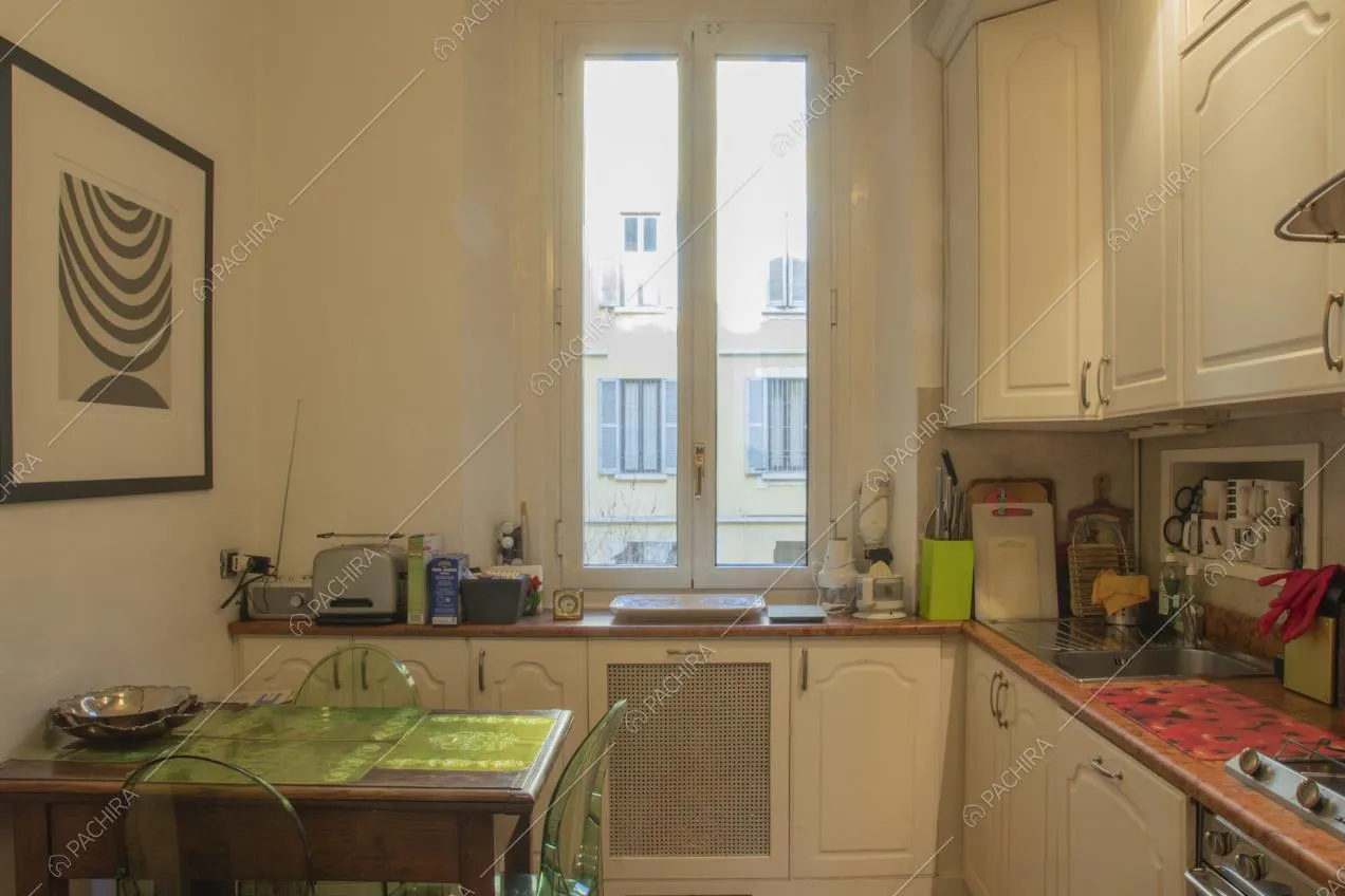 Cucina con mobili bianchi e tavolo in legno con sedie in plastica trasparente