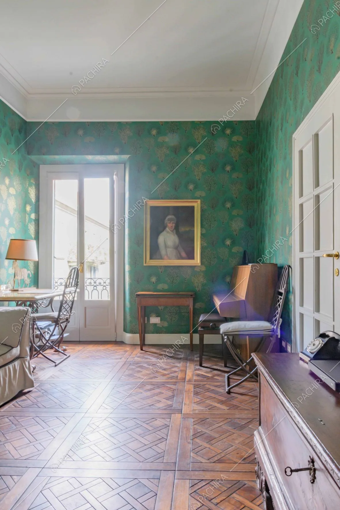 Carta da parati verde, boiserie e pavimento in parquet nel salotto con scrivania