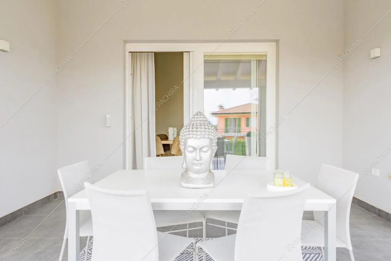 Tavolo bianco sulla terrazza da cui si accede alla zona living tramite porta-finestra