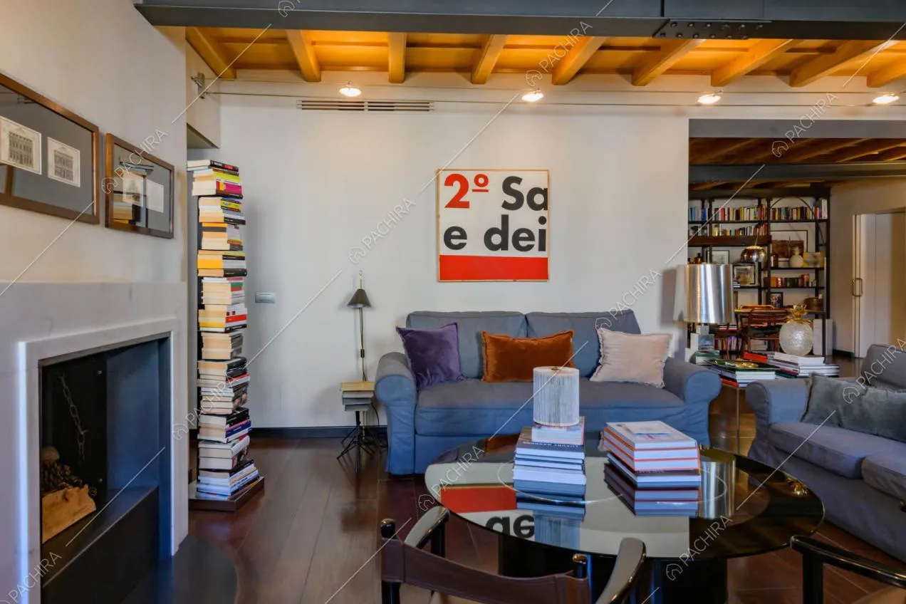 Divani grigi nel salotto con pavimento in parquet, travi in legno a vista e camino