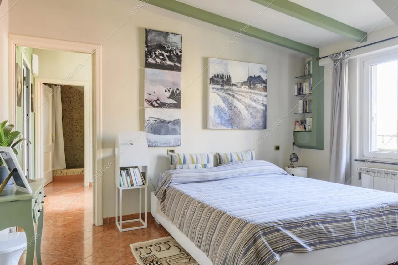 Letto, quadri appesi alla parete e finestra con tende bianche