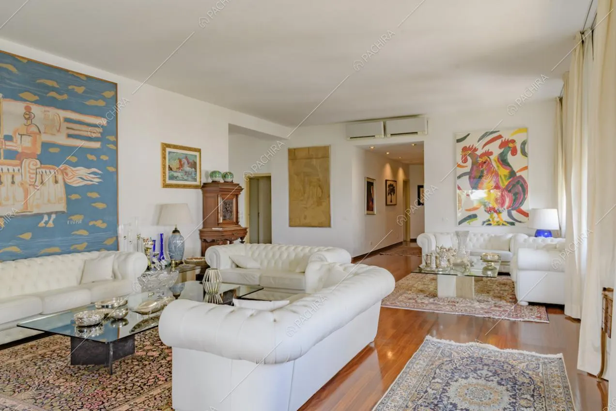 Sala con doppia zona soggiorno, grazie alla disposizione dei divani bianchi in pelle