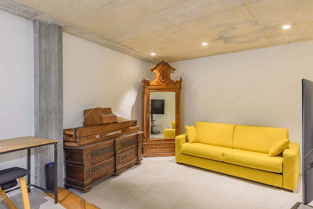 Divano giallo e soffitto in cemento nella luminosa stanza