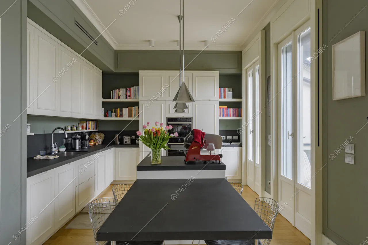 Tavolo nero con sedie in metallo nella cucina con isola e pavimento in parquet