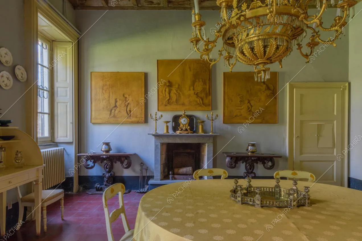 Tavolo da pranzo rotondo nella grande sala con lampadario con decorazioni dorate e camino