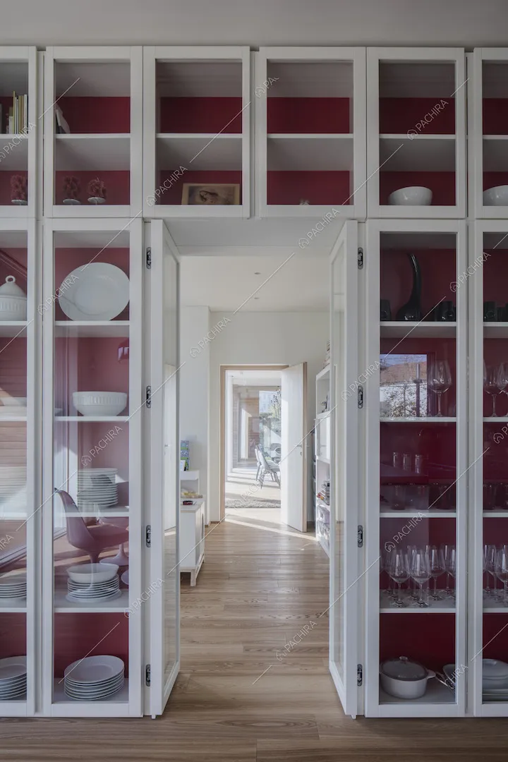 Nella cucina con il pavimento in parquet, parete rossa con credenza a tutta parete in vetro
