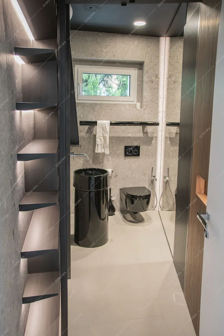 Parete in pietra nel bagno con sanitari neri e lavandino di design
