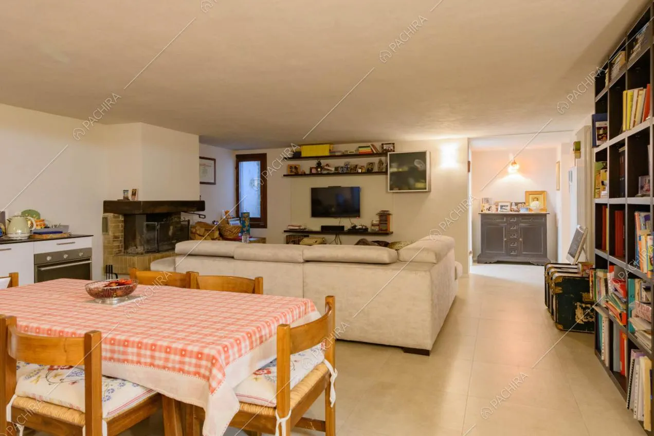 Taverna con pavimento in cemento lisciato, divano, cucina e camino