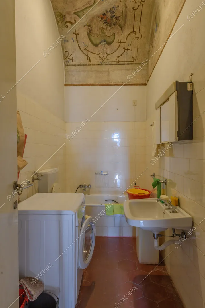 Bagno con pareti in piastrelle bianche, pavimento in cementine rosse e soffitto affrescato