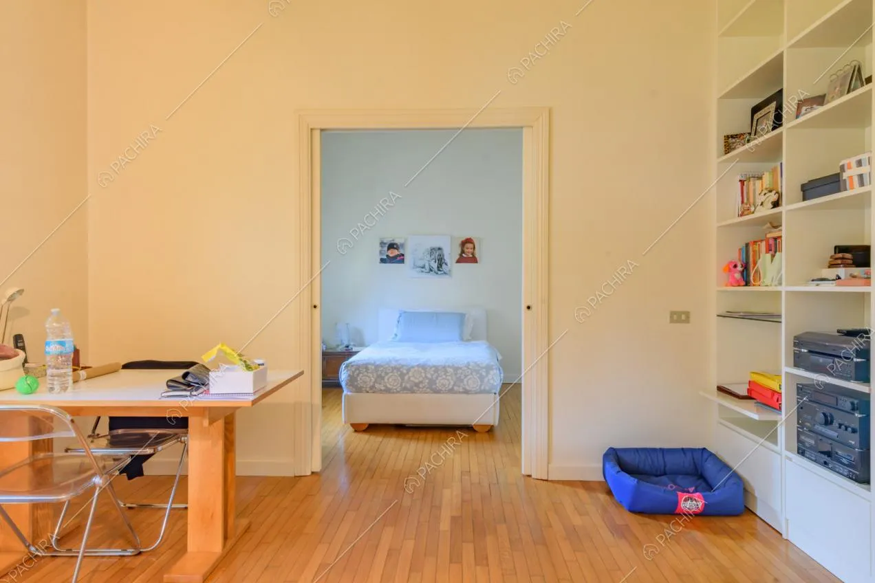 Studio con scrivania, libreria bianca e vista sulla camera da letto