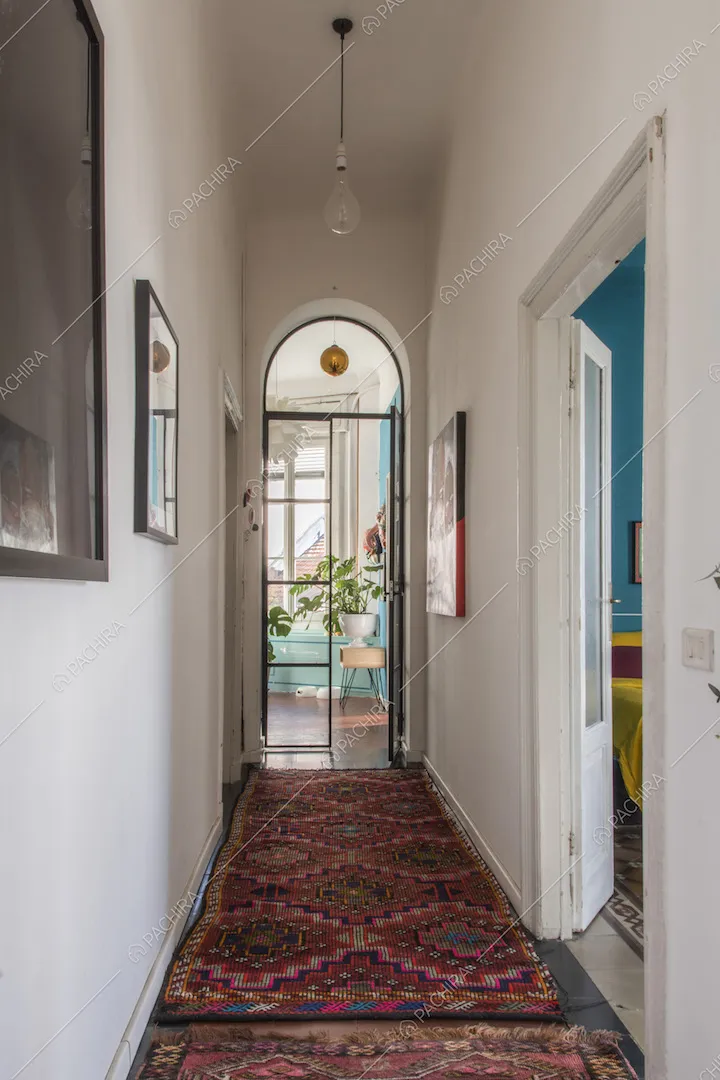 Corridoio con tappeti orientali e porta a vetri ad arco