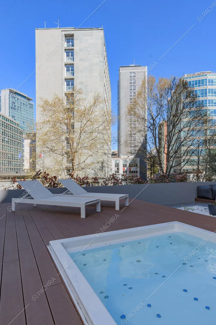 Idromassaggio e lettini bianchi sulla terrazza con pavimento in parquet da esterni