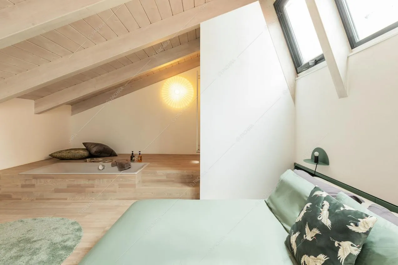 Camera da letto matrimoniale sul soppalco con lucernari, pavimento in parquet e vasca a vista