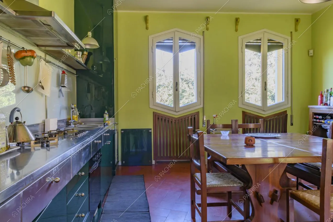 Cucina dalle pareti verde chiaro, pavimento in cotto e vista sul giardino
