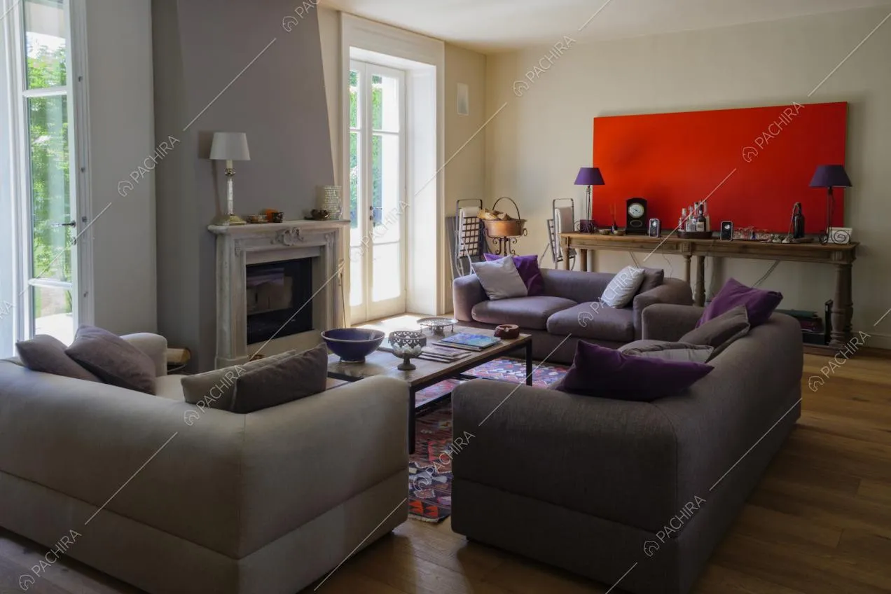 Salotto della location con tre divani, pavimento in parquet e camino