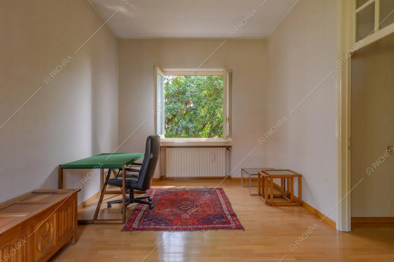 Studio con pavimento in parquet, pareti bianche e cassapanca in legno