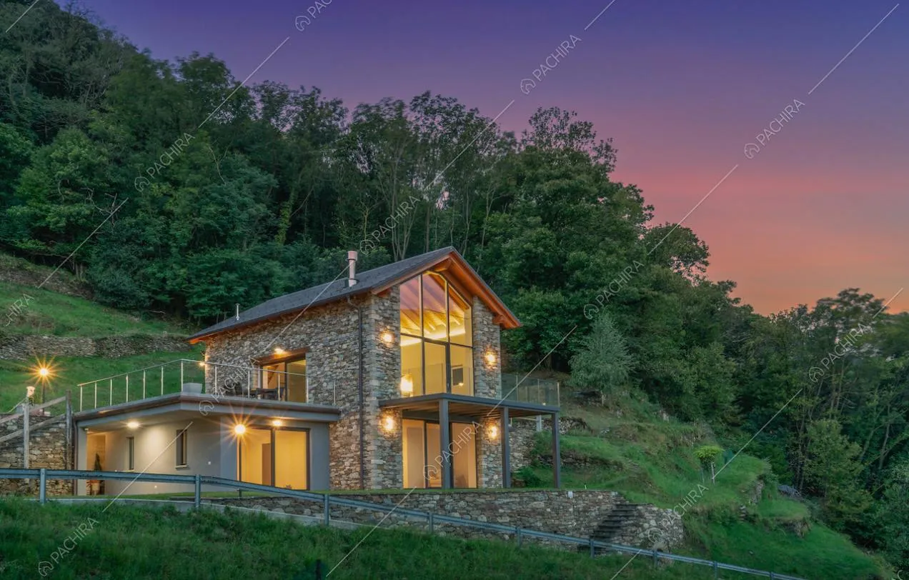 Dal giardino vista sulla villa a due piani con esterni in pietra, terrazze e verande