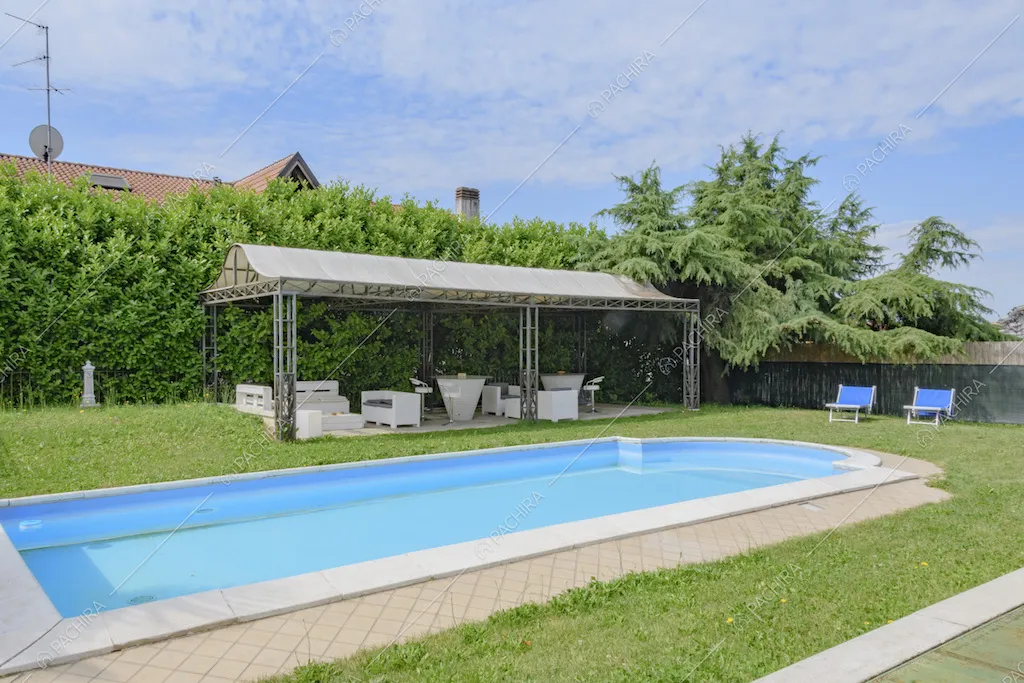 Gazebo e area relax con sedie e tavolini di fianco alla piscina