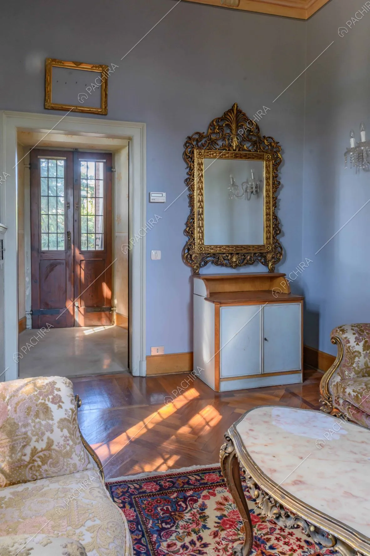 Salotto dalle pareti azzurre con arredamento in stile antico e pavimento in parquet 