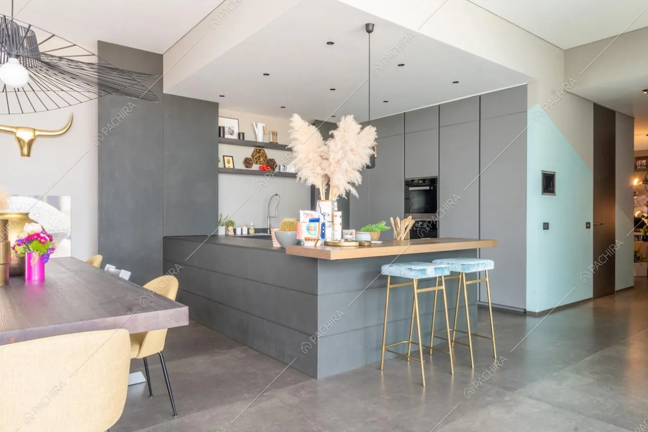 Dal tavolo da pranzo vista sulla cucina con penisola, bancone in legno e sgabelli