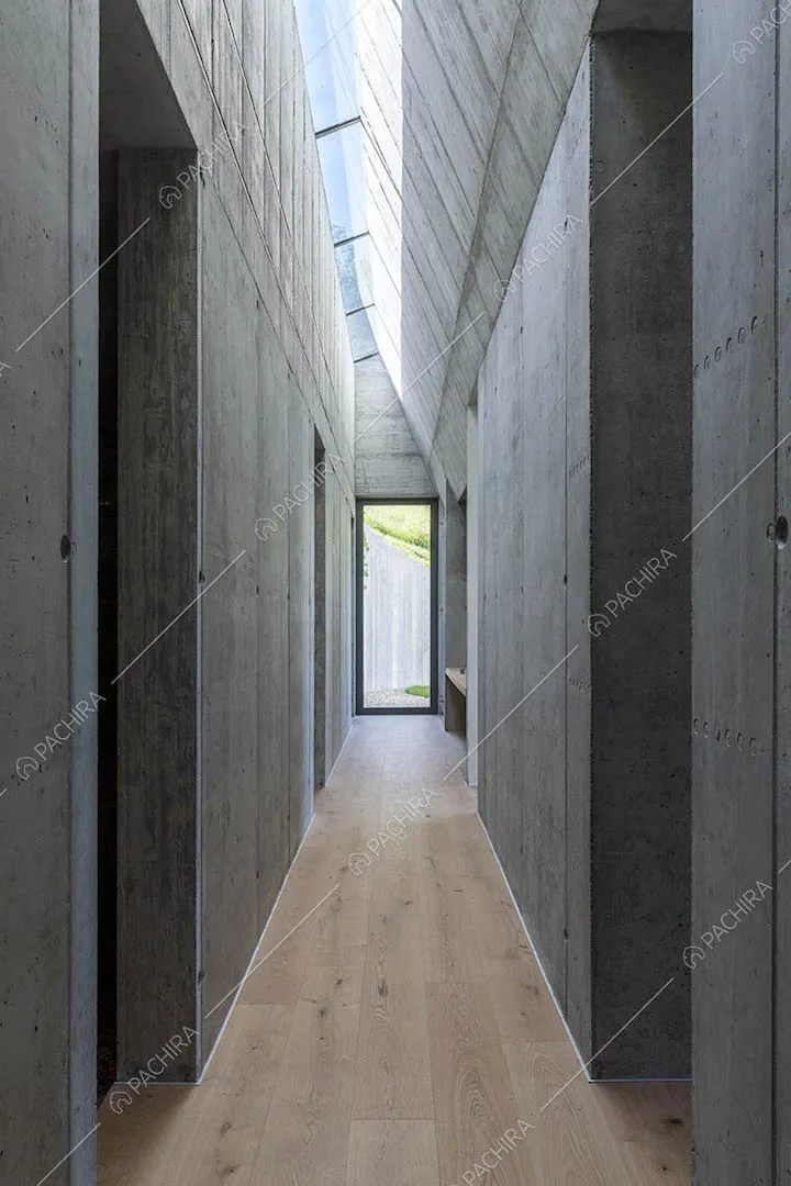 Corridoio con pavimento in parquet, pareti in cemento e lucernari