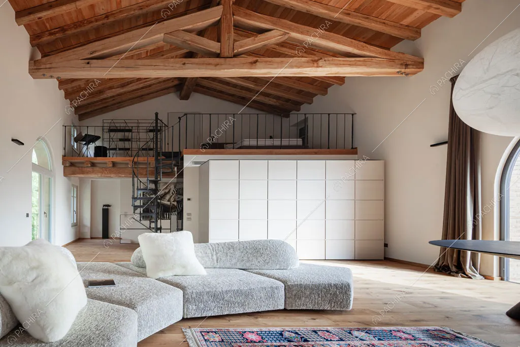 Luminosa sala con travi a vista sul soffitto e soppalco nella villa Ghibli, location in stile contemporaneo a Verona