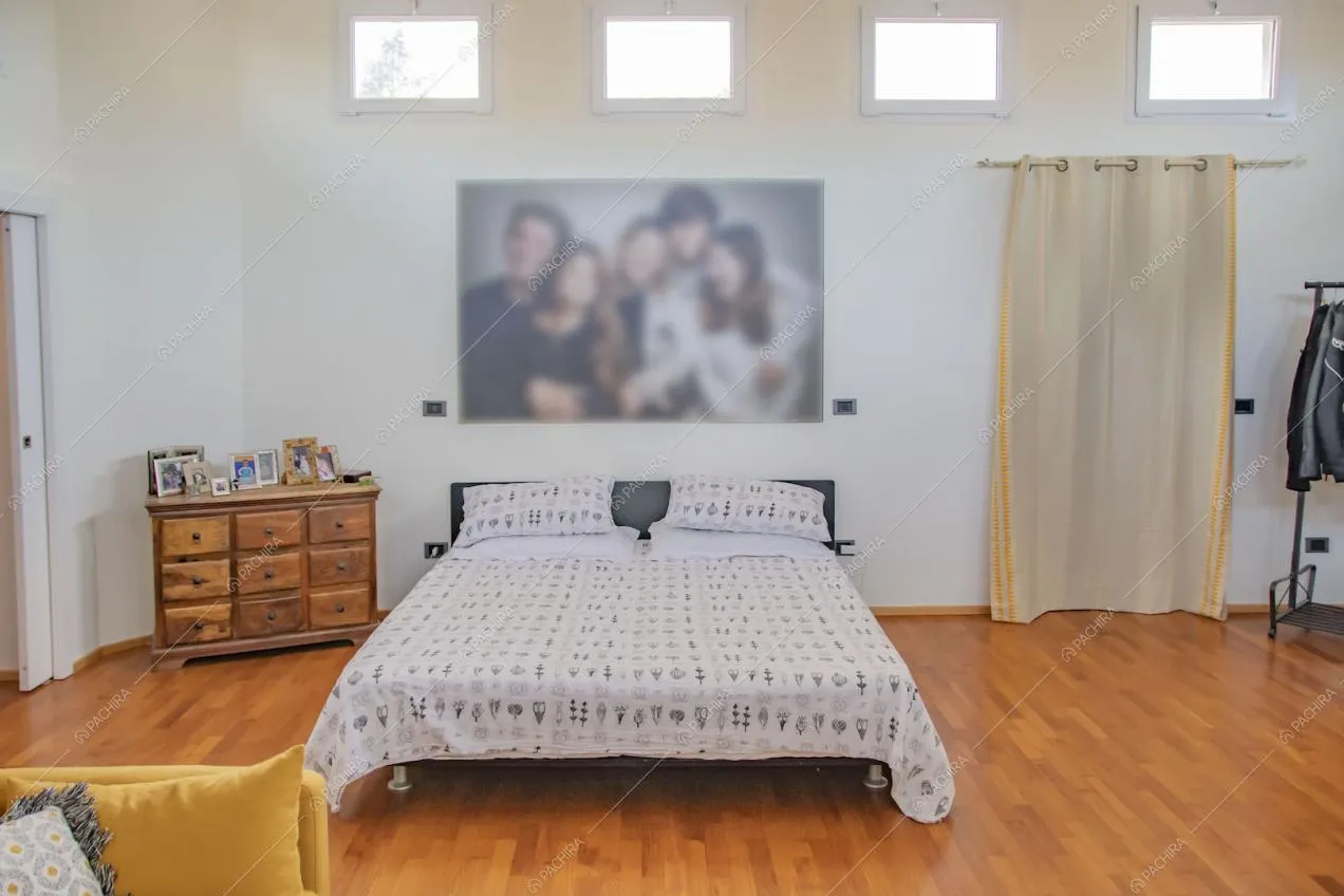 Luminosa camera da letto matrimoniale con pavimento in parquet e pareti bianche