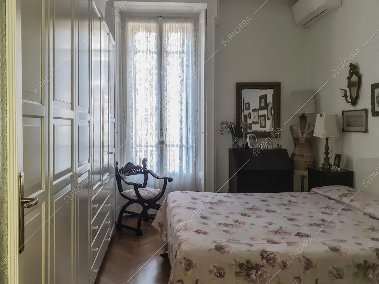Camera matrimoniale con grande armadio bianco e sedia antica in legno con cuscino