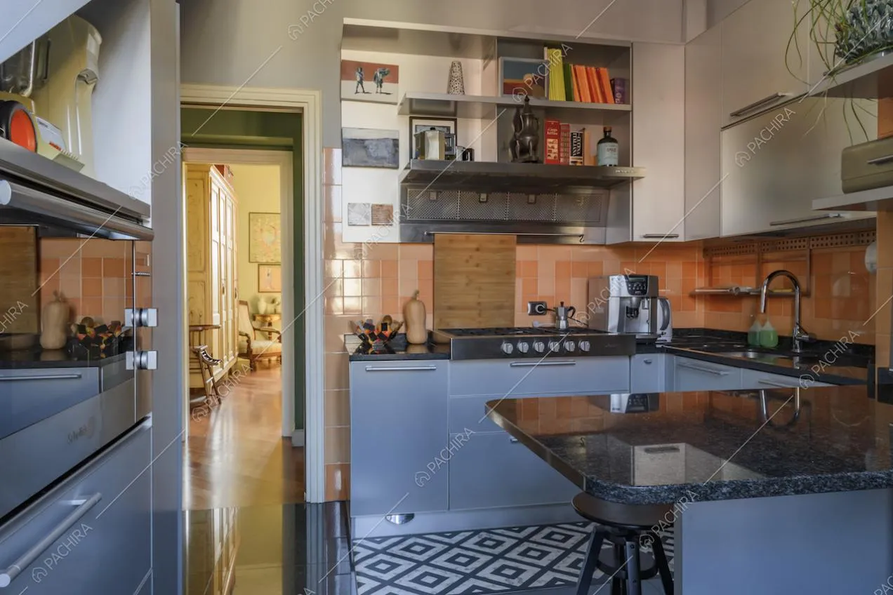 Cucina con mobili chiari e piano di lavoro in marmo