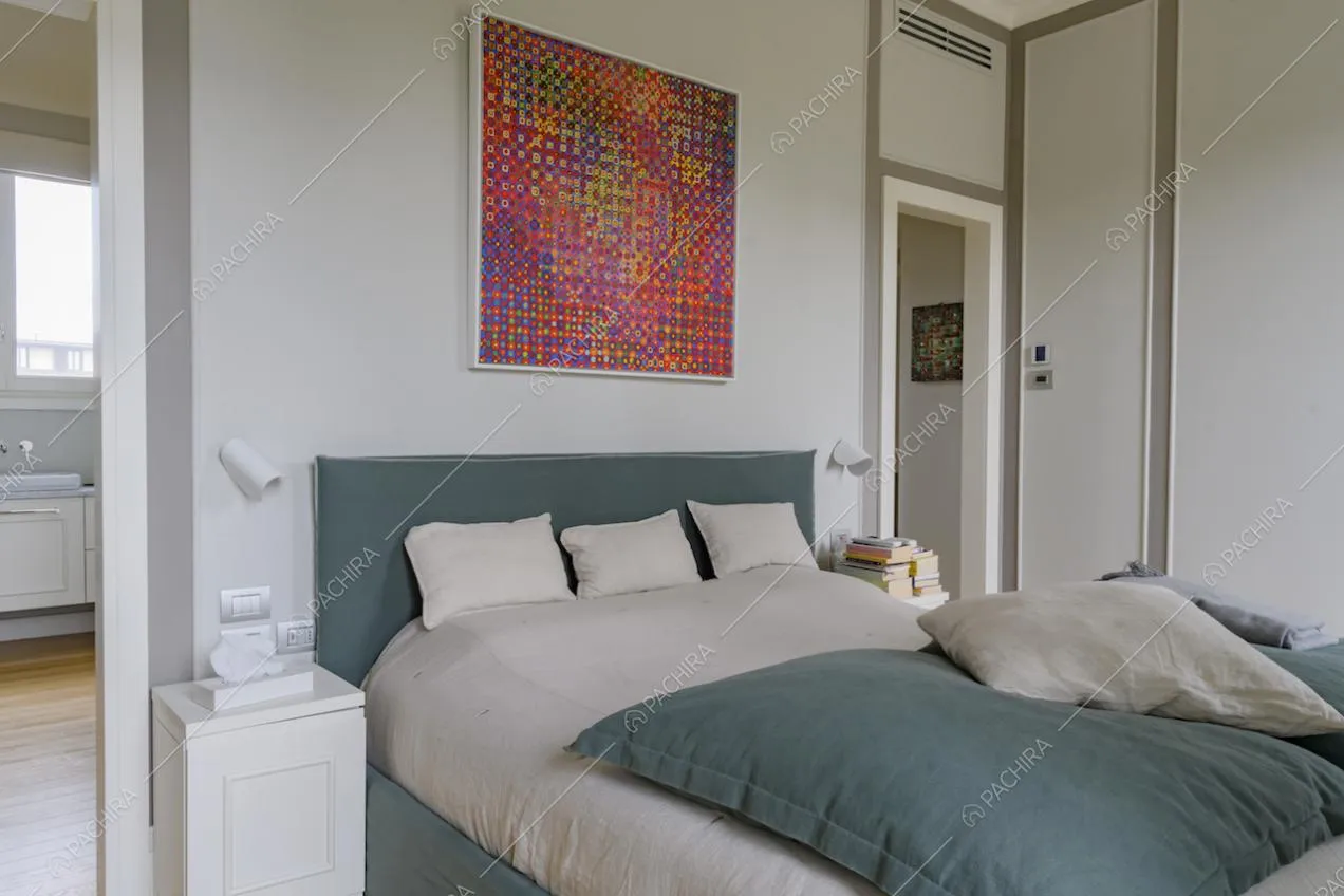 Letto matrimoniale in camera dalle pareti grigie e con boiserie