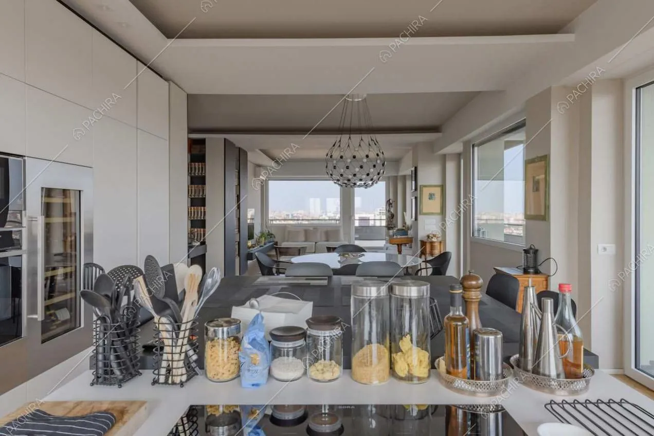 Fornelli a induzione sull'isola della cucina con tavolo accostato e vista sulla sala
