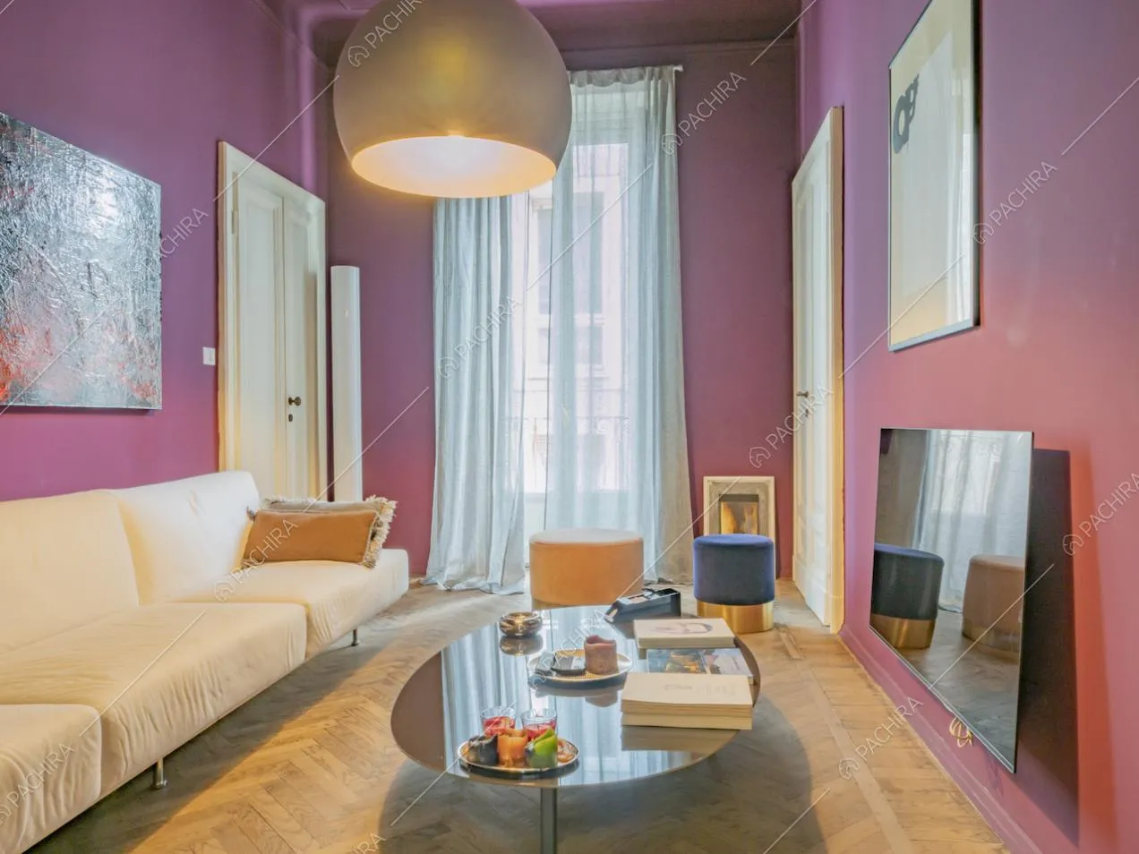 Tavolino ovale, pouf tondi in velluto colorato su pavimento in parquet