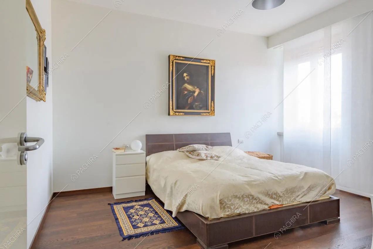 Camera da letto matrimoniale con pavimento in parquet e pareti bianche