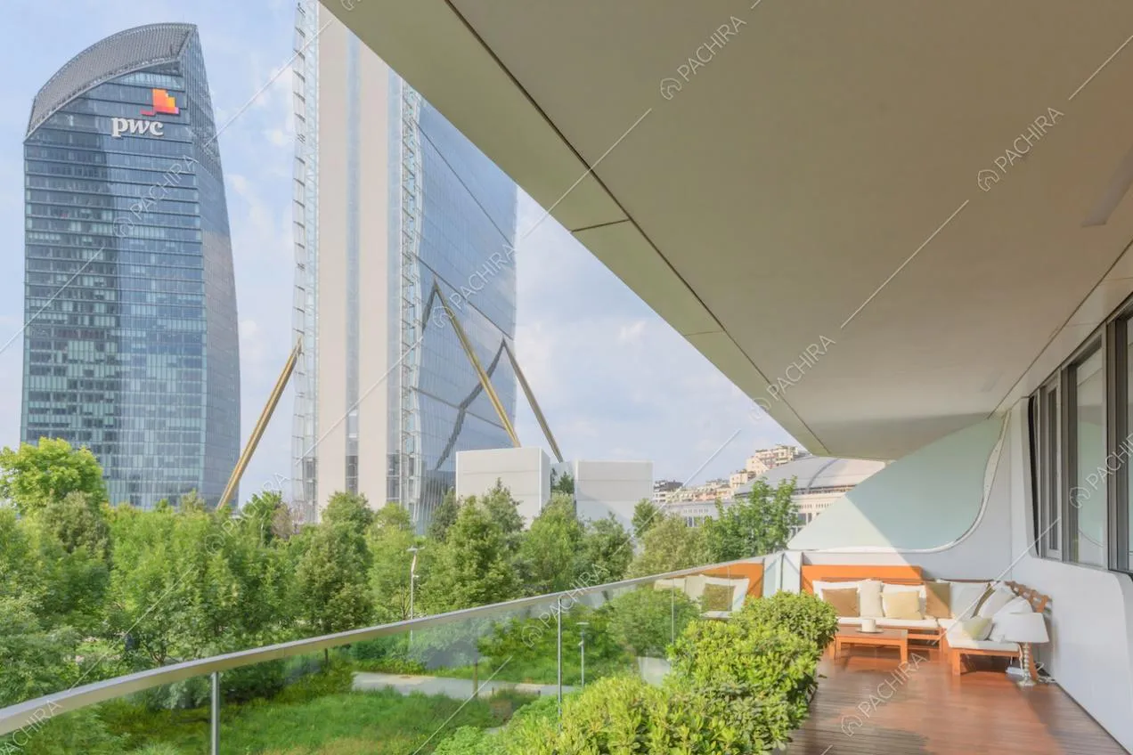 Parapetto in vetro sulla terrazza coperta, con salotto da esterni e vista sullo skyline