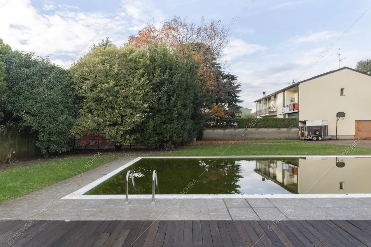 Piscina con bordi in pietra e legno nel giardino della villa
