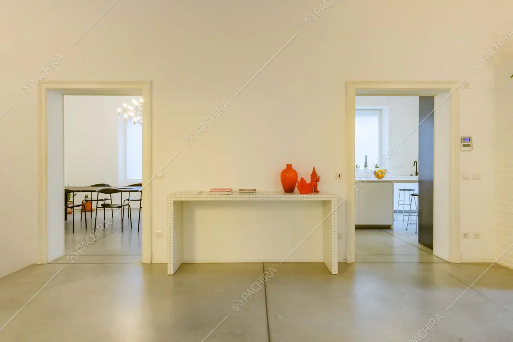 Tavolo di design con quadri bianchi nella zona living con scorcio sull'isola della cucina