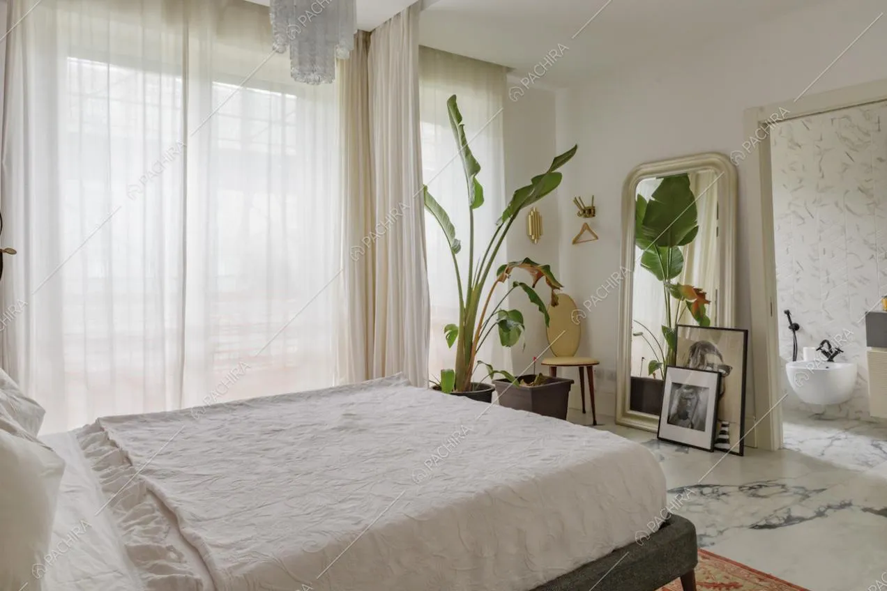 Letto matrimoniale in luminosa camera da letto con bagno privato e lampadario antico