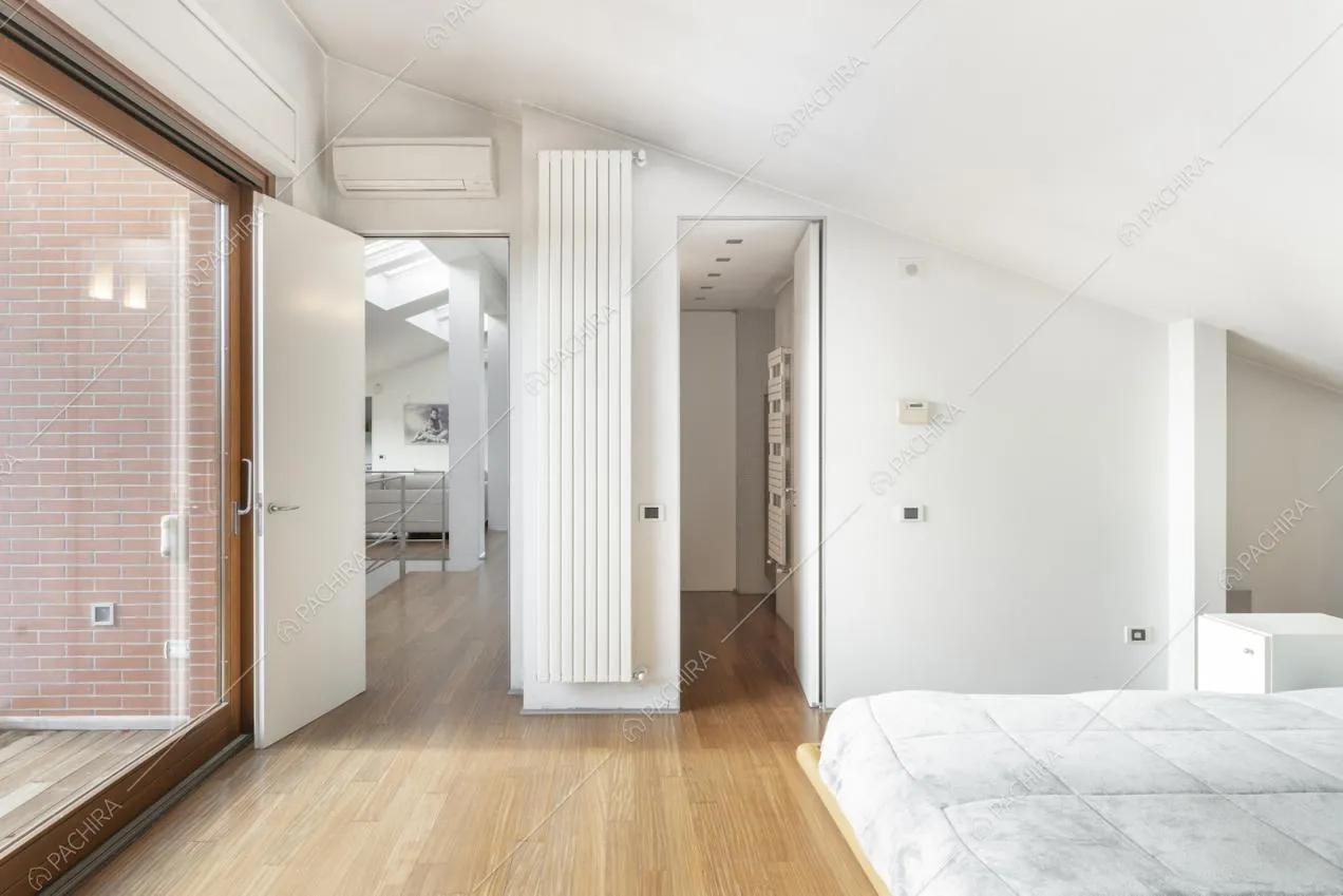 Camera da letto nel sottotetto con grande vetrata e parquet