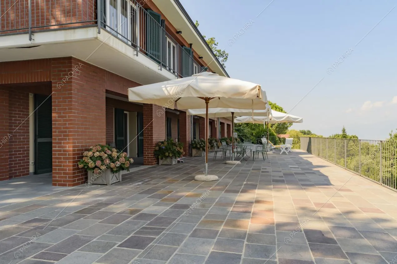 Terrazza con ombrelloni da giardino ed esterni della villa in mattoni rossi a vista
