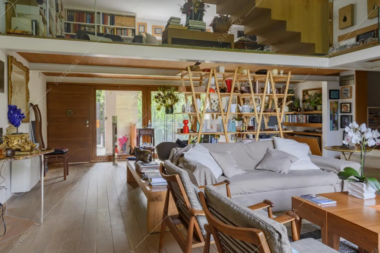 Soggiorno con poltroncine in legno, divano e libreria in legno